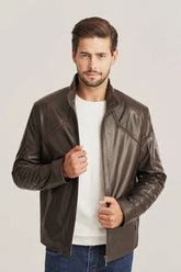Man wearing a brown leather jacket over a white shirt on a light gray background