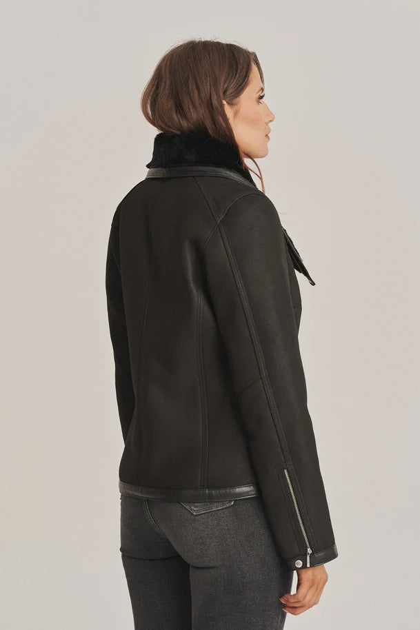 Person wearing a black leather jacket with fur collar on a plain background