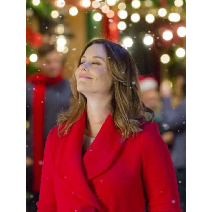 Woman in a red coat standing in front of Christmas lights