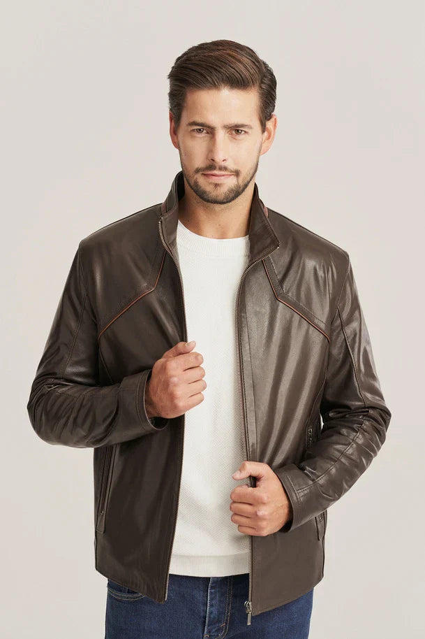 Man wearing a brown leather jacket over a white shirt on a light gray background