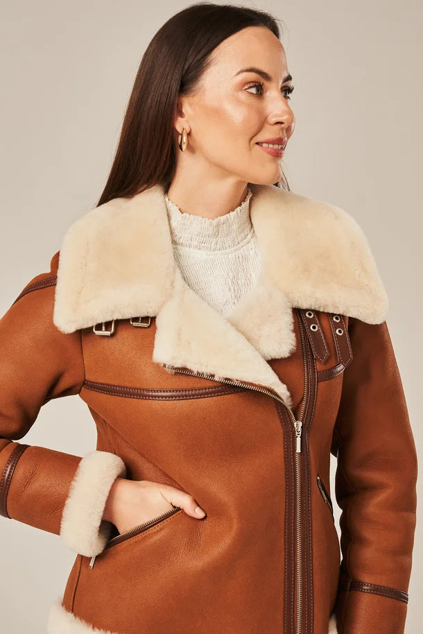 Woman wearing a brown leather coat with white fur collar against a neutral background