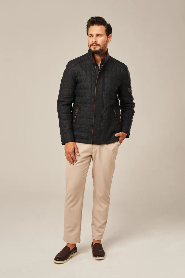 Man wearing a black quilted jacket and beige pants on a beige background