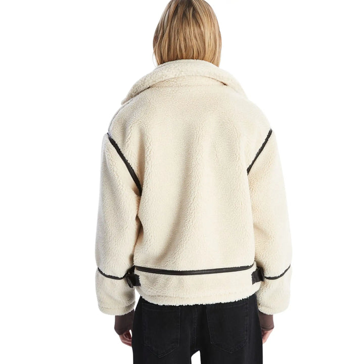 Person wearing a cream-colored jacket with black accents on a white background