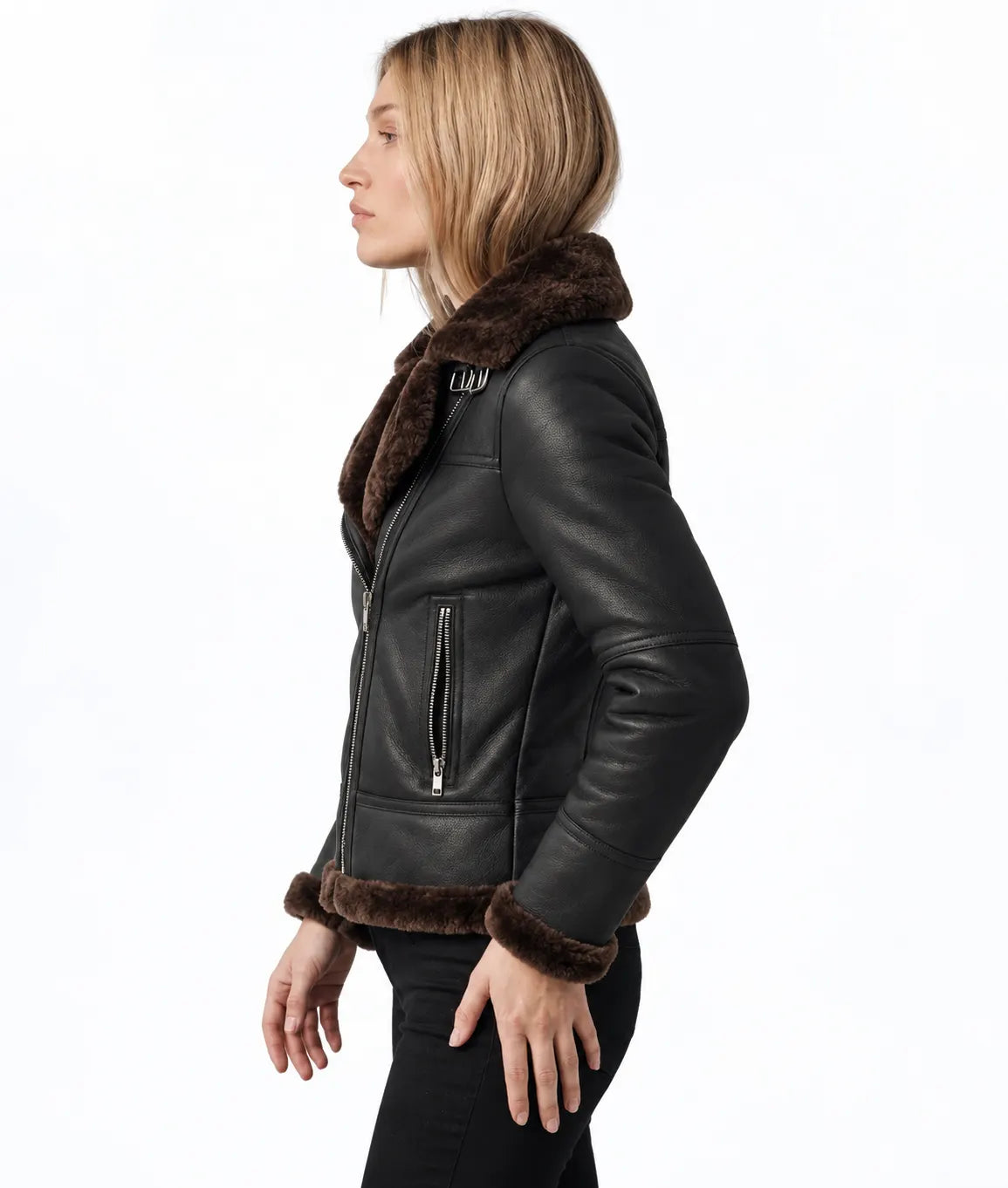 A woman shown in profile wearing a black leather aviator-style jacket with dark brown faux-fur trim on the collar, cuffs, and hem, paired with black pants, against a plain white background.
